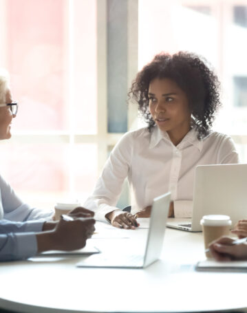 Serious african american female leader talking at diverse group boardroom meeting, multi-ethnic team people employees discussing deal benefits, negotiating on business contract terms with clients