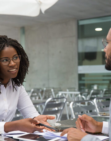 Businesswoman consulting legal experts in coffee shop. Business man and woman meeting in street cafe, talking and smiling. Business discussion concept